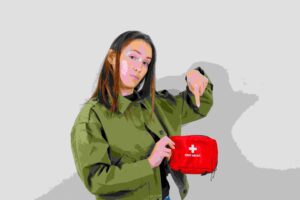 Person holding and pointing to a red first aid kit, emphasizing emergency preparedness.